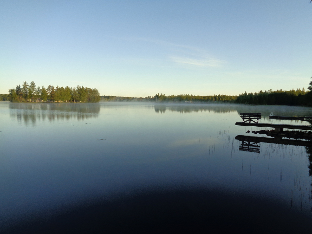 Sumuinen järvi valoisassa kesäyössä.